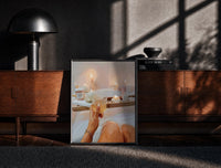 Black-framed Candlelit Bath with a Drink print on the floor in front of a dark wooden console
