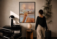 Candlelit Bath with a Drink print in a black frame on a sunlit plaster wall, a woman looking on beside a mushroom lamp