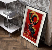Woman dancing with champagne bottle poster in a black frame leaning beside a shelf in a raw-plaster loft