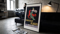 Woman in green riding red horse print in a slim black frame leaning on a dark sofa in a concrete print studio