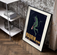 Green devil holding aperitif bottle poster in a black frame leaning beside a shelf in a raw-plaster loft