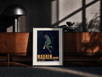 Black-framed Green devil holding aperitif bottle print on a moody console with designer coffee-table books