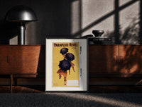 Black-framed People walking with black umbrellas print on a moody console with designer coffee-table books