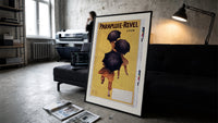 People walking with black umbrellas print in a slim black frame leaning on a dark sofa in a concrete print studio