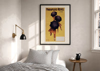 Cappiello Parapluie-Revel figures under black umbrellas print in a black frame above a bed with striped linens