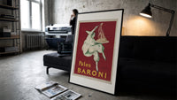 Pierrot serving plate of spaghetti print in a slim black frame leaning on a dark sofa in a concrete print studio