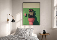 Cat on the Toilet Reading the Paper print in a black frame above a bed with striped linens