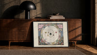 Antique celestial planisphere star chart print in a black frame leaning against a walnut console in lamplight