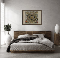 Copernican solar system celestial map print in a dark wood frame above a rattan bed on a plaster wall