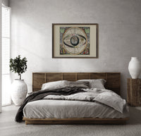 Ptolemaic celestial sphere armillary map print in a dark wood frame above a rattan bed on a plaster wall