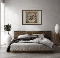 Ptolemaic celestial system with globe print in a dark wood frame above a rattan bed on a plaster wall