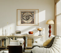 Ptolemaic celestial system with globe print in an oak frame above a mid-century book console with a vintage radio