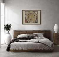 Ptolemaic celestial map of universe print in a dark wood frame above a rattan bed on a plaster wall