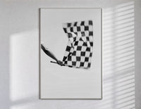Hand waving checkered racing flag poster in a slim frame on a bright wall with soft window light