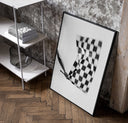 Hand waving checkered racing flag poster in a black frame leaning beside a shelf in a raw-plaster loft