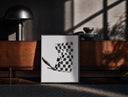 Black-framed Hand waving checkered racing flag print on a moody console with designer coffee-table books