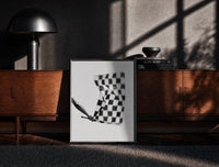 Black-framed Hand waving checkered racing flag print on a moody console with designer coffee-table books