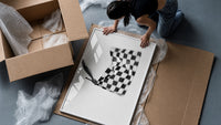 Hand waving checkered racing flag framed print being unpacked from protective bubble wrap and a box