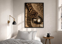 Cheetah Paw and Disco Ball print in a black frame above a bed with striped linens, a brass wall lamp and a sunlit window