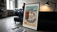 Laughing clown face print in a slim black frame leaning on a dark sofa in a concrete print studio