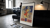 Children riding horses with fireworks print in a slim black frame leaning on a dark sofa in a concrete print studio