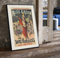 Female conductor leading violin orchestra print in a black frame leaning beside a vintage door on parquet