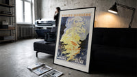 Woman dancing in flames print in a slim black frame leaning on a dark sofa in a concrete print studio