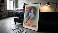 Elegant woman in pink dress print in a slim black frame leaning on a dark sofa in a concrete print studio