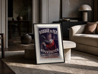 Man in red cloak holding iron mask print in a black frame leaning on a travertine table in a sunlit lounge
