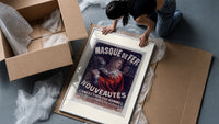 Man in red cloak holding iron mask framed print being unpacked from protective bubble wrap and a box