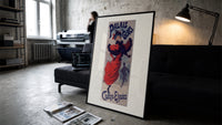 Woman ice skating in red dress print in a slim black frame leaning on a dark sofa in a concrete print studio