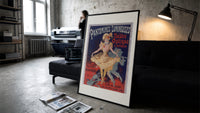 Dancing woman in yellow dress print in a slim black frame leaning on a dark sofa in a concrete print studio