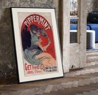 Woman pouring liqueur into glass print in a black frame leaning beside a vintage door on parquet