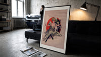 Woman with wine glass and cat print in a slim black frame leaning on a dark sofa in a concrete print studio
