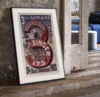 Woman using Singer sewing machine print in a black frame leaning beside a vintage door on parquet