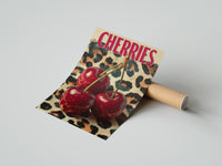 Gently curled Cherries on Leopard print beside its protective shipping tube