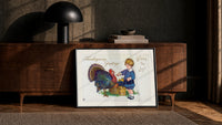 Child and Turkey Wishing You Joy print in a black frame leaning against a walnut sideboard
