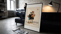 Two children holding Santa doll print in a slim black frame leaning on a dark sofa in a concrete print studio
