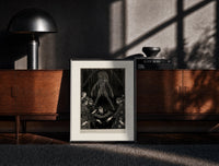 Black-framed Ghostly figure looming over frightened men print on a moody console with designer coffee-table books