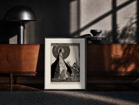 Black-framed ethereal woman and shrouded man print on a moody console with designer coffee-table books