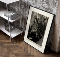 chained man in dungeon catacomb poster in a black frame leaning beside a shelf in a raw-plaster loft