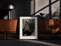 Black-framed chained man in dungeon catacomb print on a moody console with designer coffee-table books