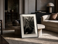 chained man in dungeon catacomb print in a black frame leaning on a travertine table in a sunlit lounge