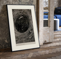 Boat caught in whirlpool vortex print in a black frame leaning beside a vintage door on parquet