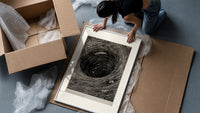 Boat caught in whirlpool vortex framed print being unpacked from protective bubble wrap and a box