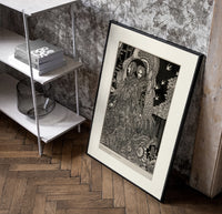 Two ornately robed figures embracing poster in a black frame leaning beside a shelf in a raw-plaster loft