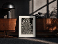 Black-framed Two ornately robed figures embracing print on a moody console with designer coffee-table books