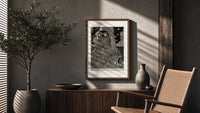 Two ornately robed figures embracing poster framed above a fluted sideboard beside an olive tree