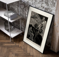 Man carrying pale woman, seated figure poster in a black frame leaning beside a shelf in a raw-plaster loft