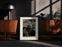 Black-framed Man carrying pale woman, seated figure print on a moody console with designer coffee-table books